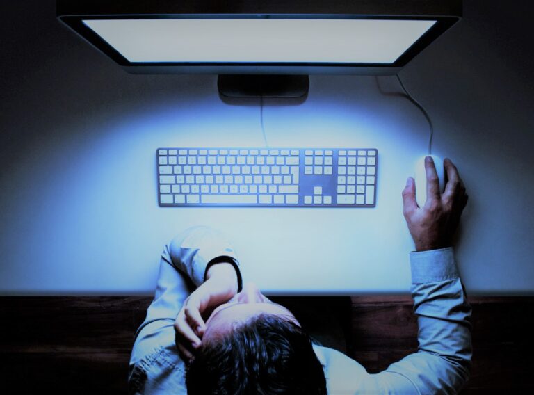 Man sitting at glowing computer screen in darkness